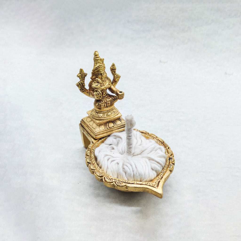 Decorative gold statue on a white pedestal with a white cushioned base on a light gray background