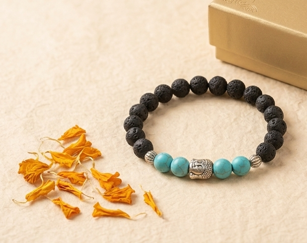 Black beaded bracelet with turquoise beads and silver accents on a beige surface with dried flowers.