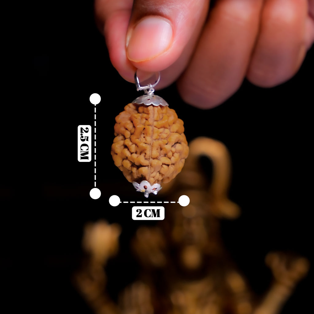 Hand holding a pendant with measurement details against a dark background