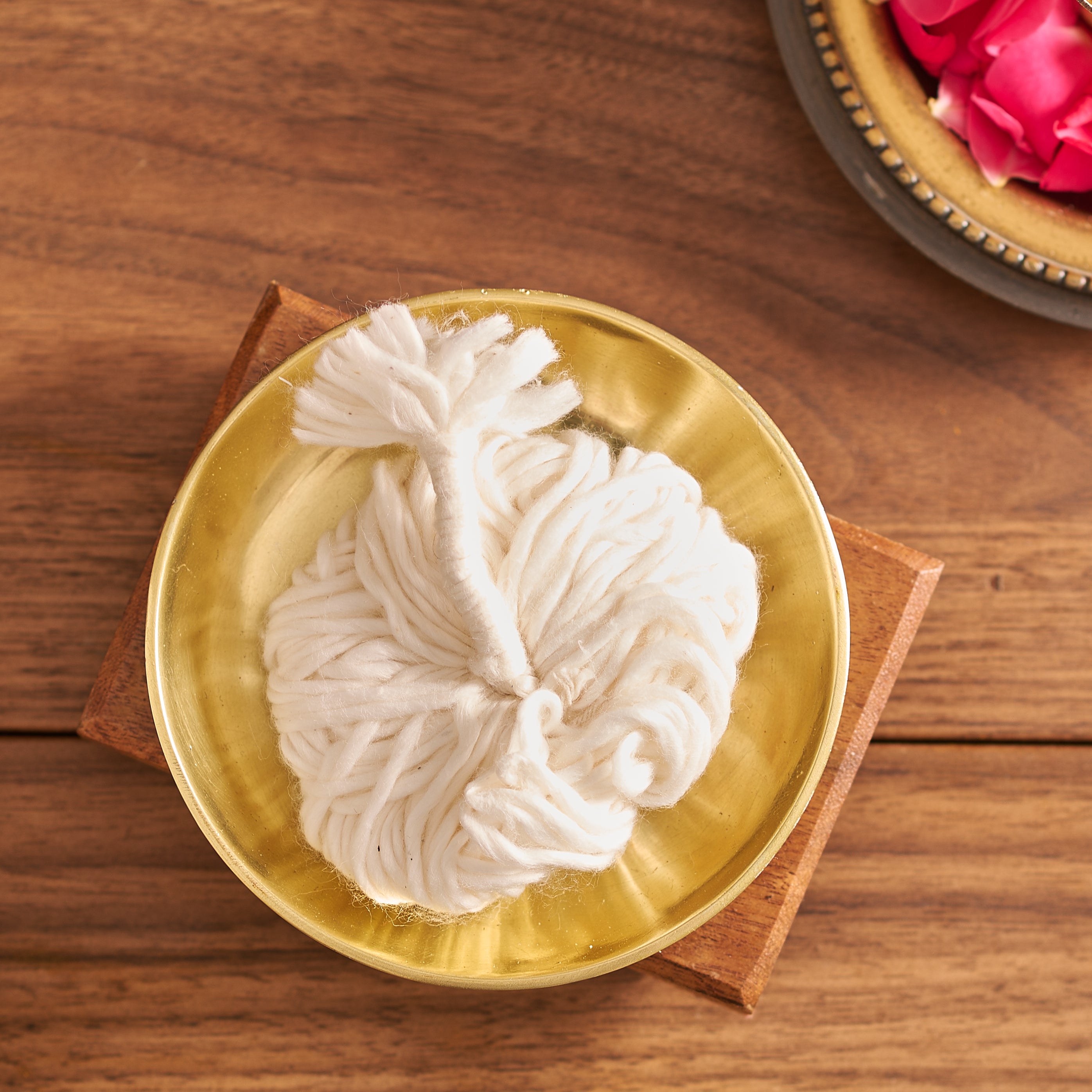 Decorative white flower on a gold plate with a wooden base on a wooden surface