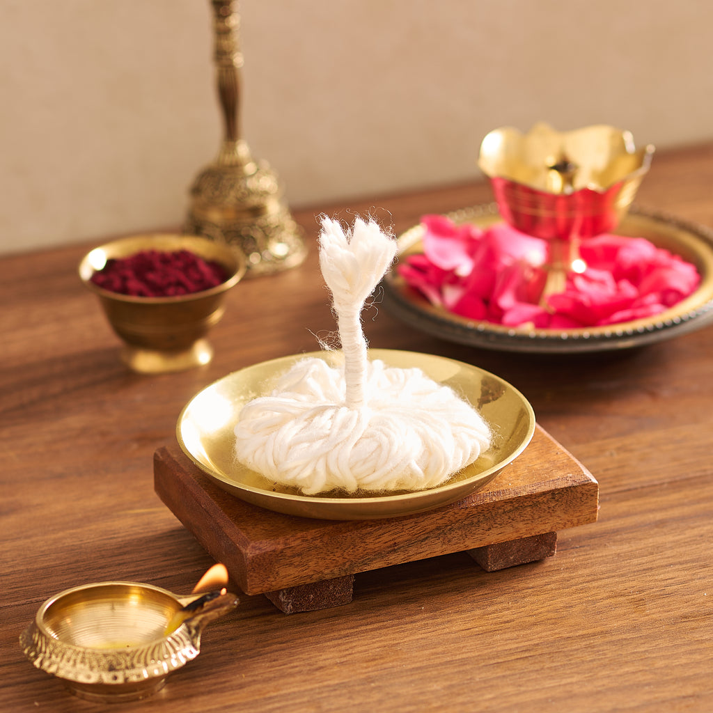 Incense stick burning in a gold dish on a wooden table with decorative items in the background.