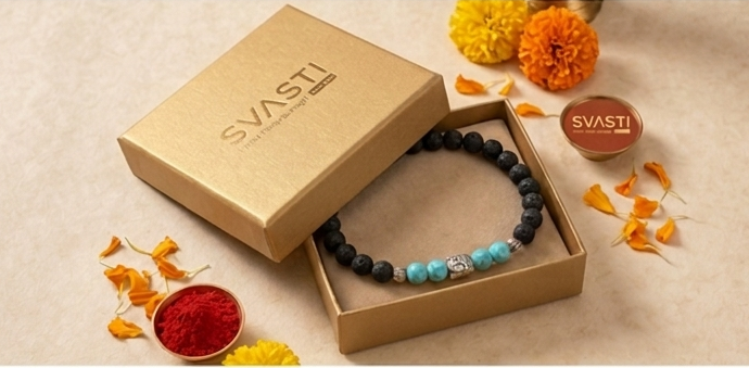 Bracelet in an open box with 'SVASTI' branding, surrounded by flowers and a small bowl of red powder on a beige background.