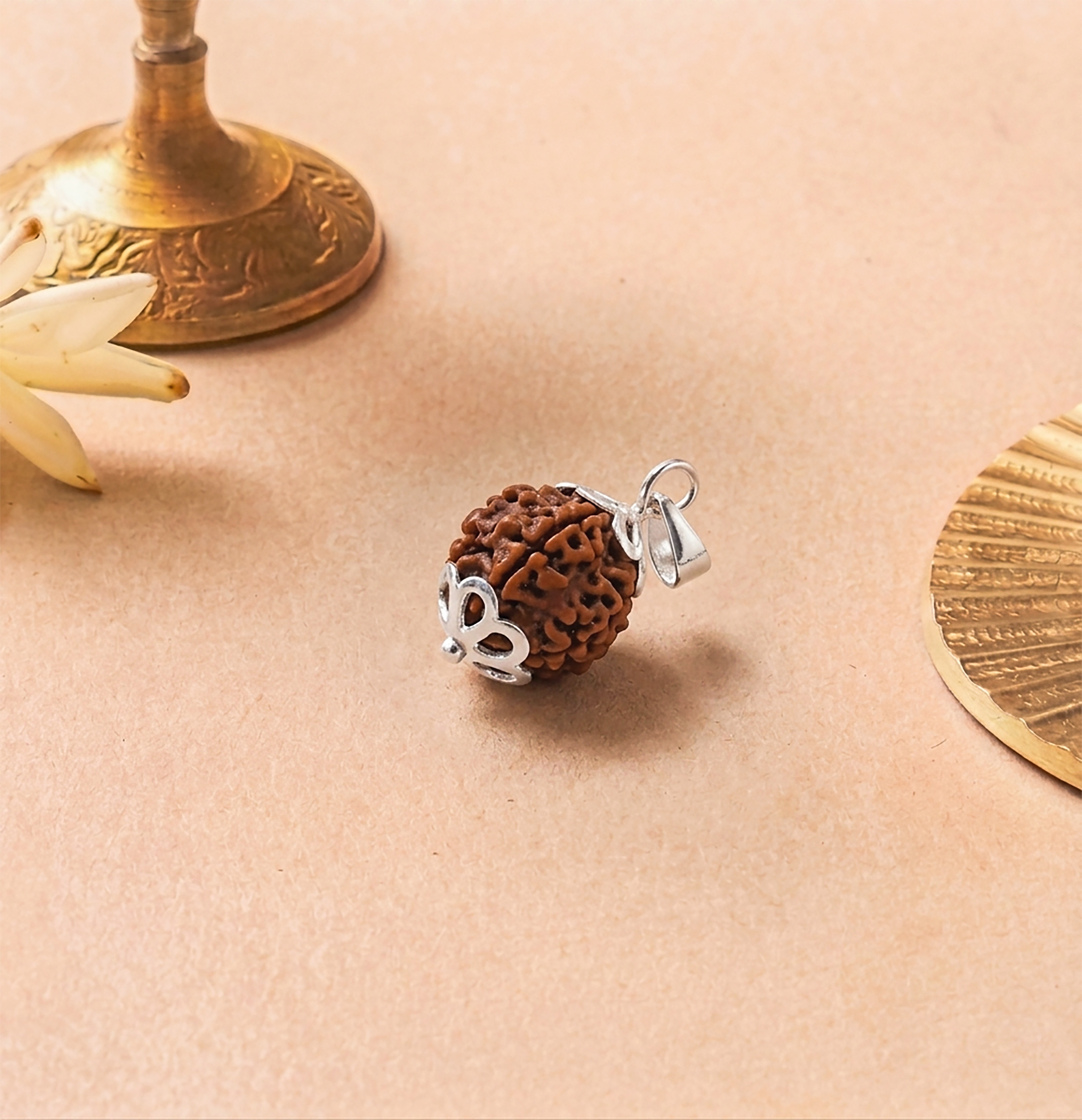 Brown textured pendant with silver heart charm on a beige surface