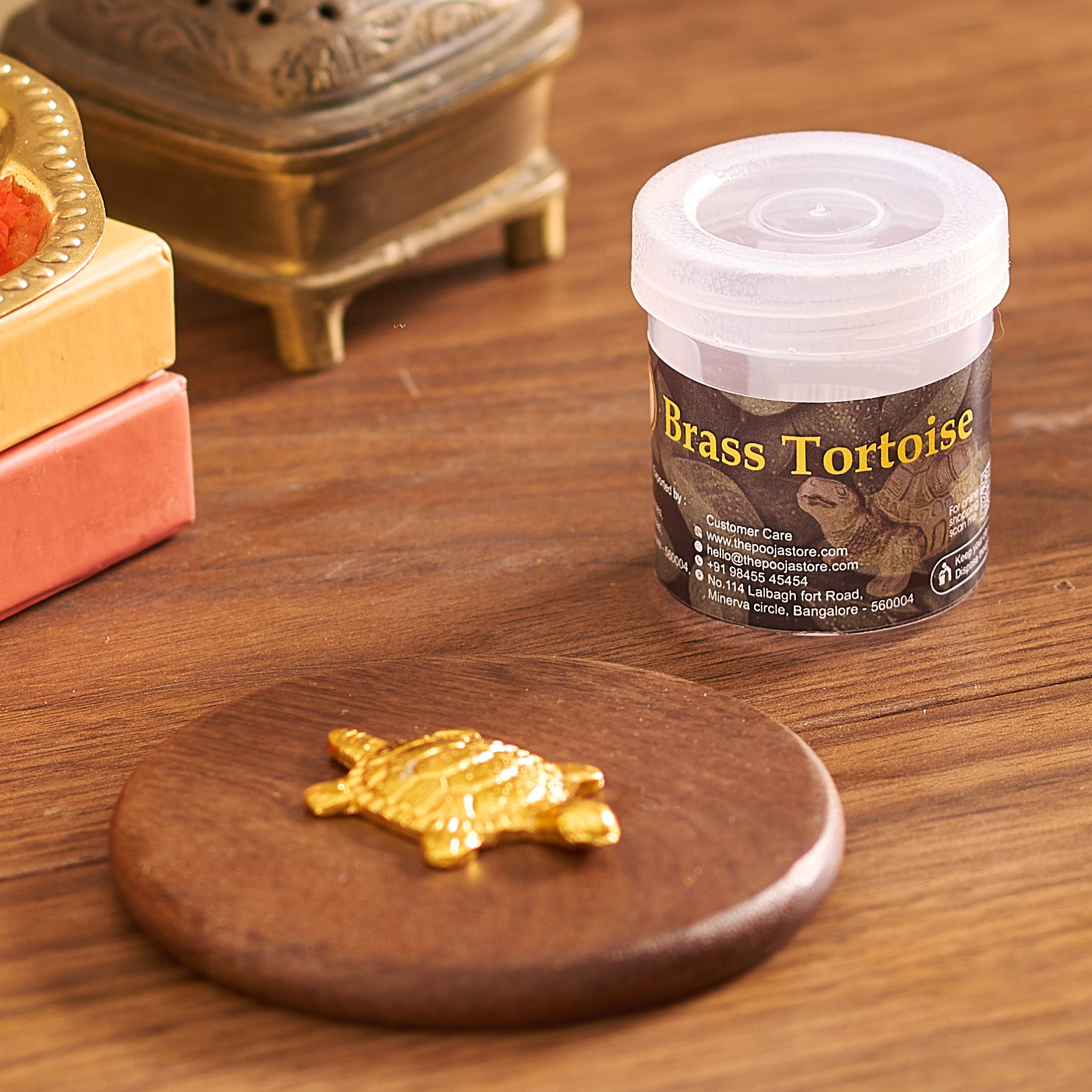 Gold tortoise figurine on a wooden coaster with a container labeled 'Brass Tortoise' in the background.