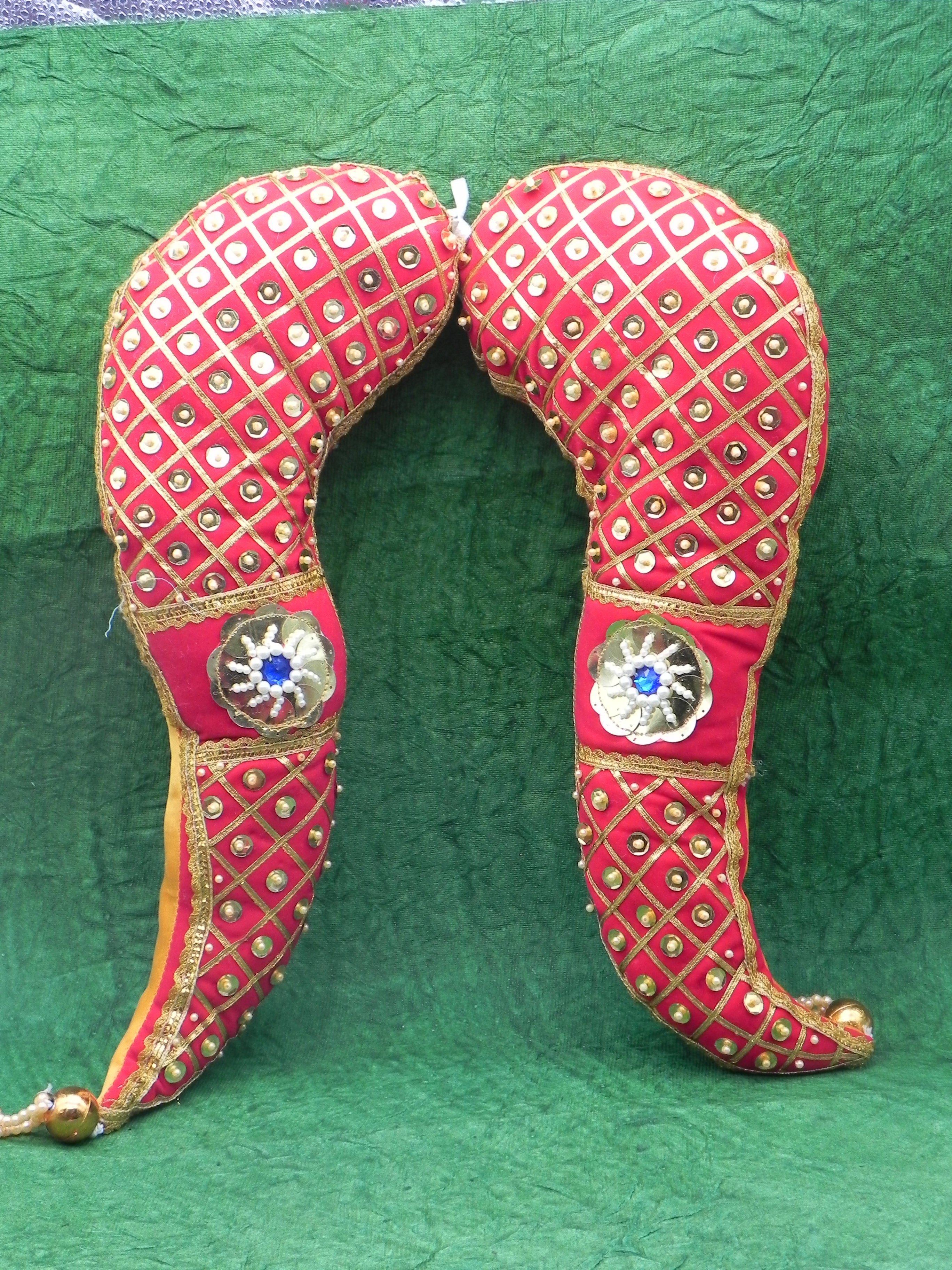Decorative red and gold headgear with intricate patterns on a green background