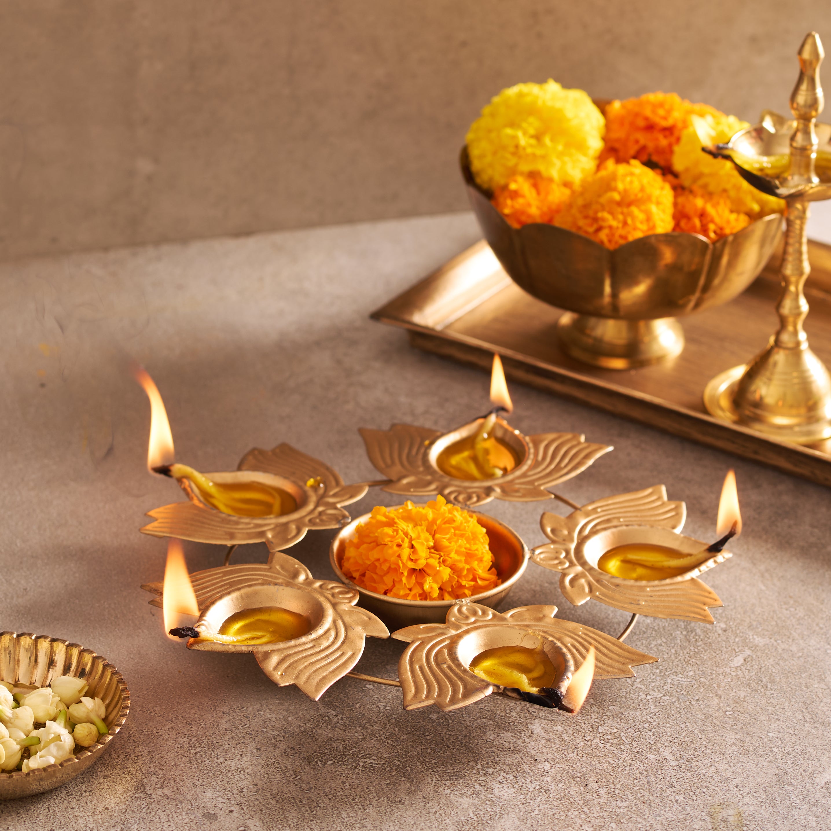 Decorative oil lamps with marigold flowers on a stone surface