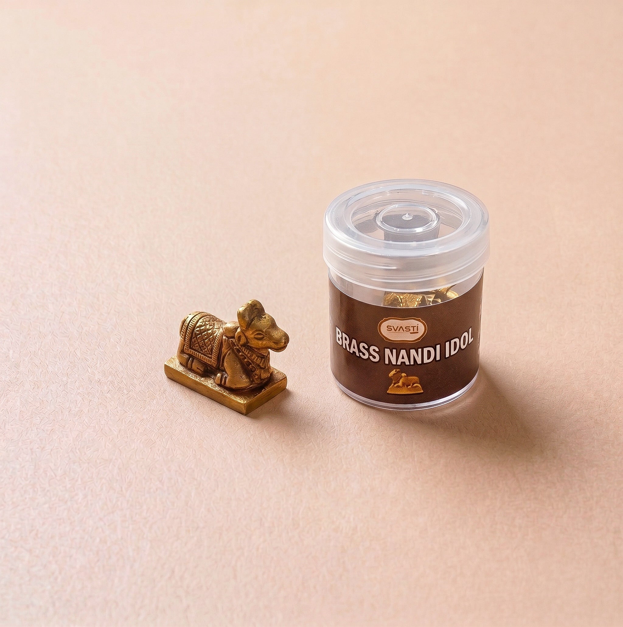 Brass Nandi idol next to a container labeled 'Brass Nandi Idol' on a beige background
