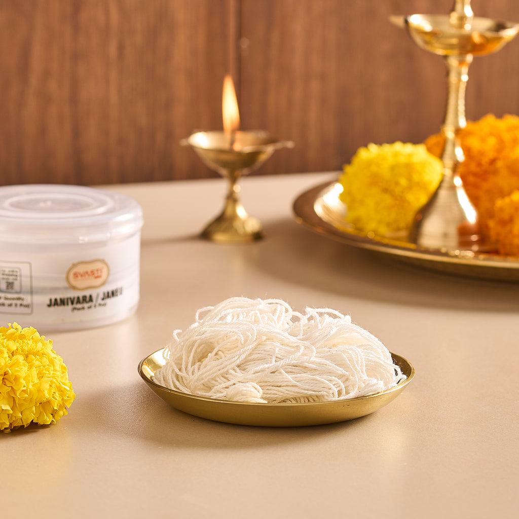 Noodles on a gold plate with decorative marigold flowers and a candle in the background