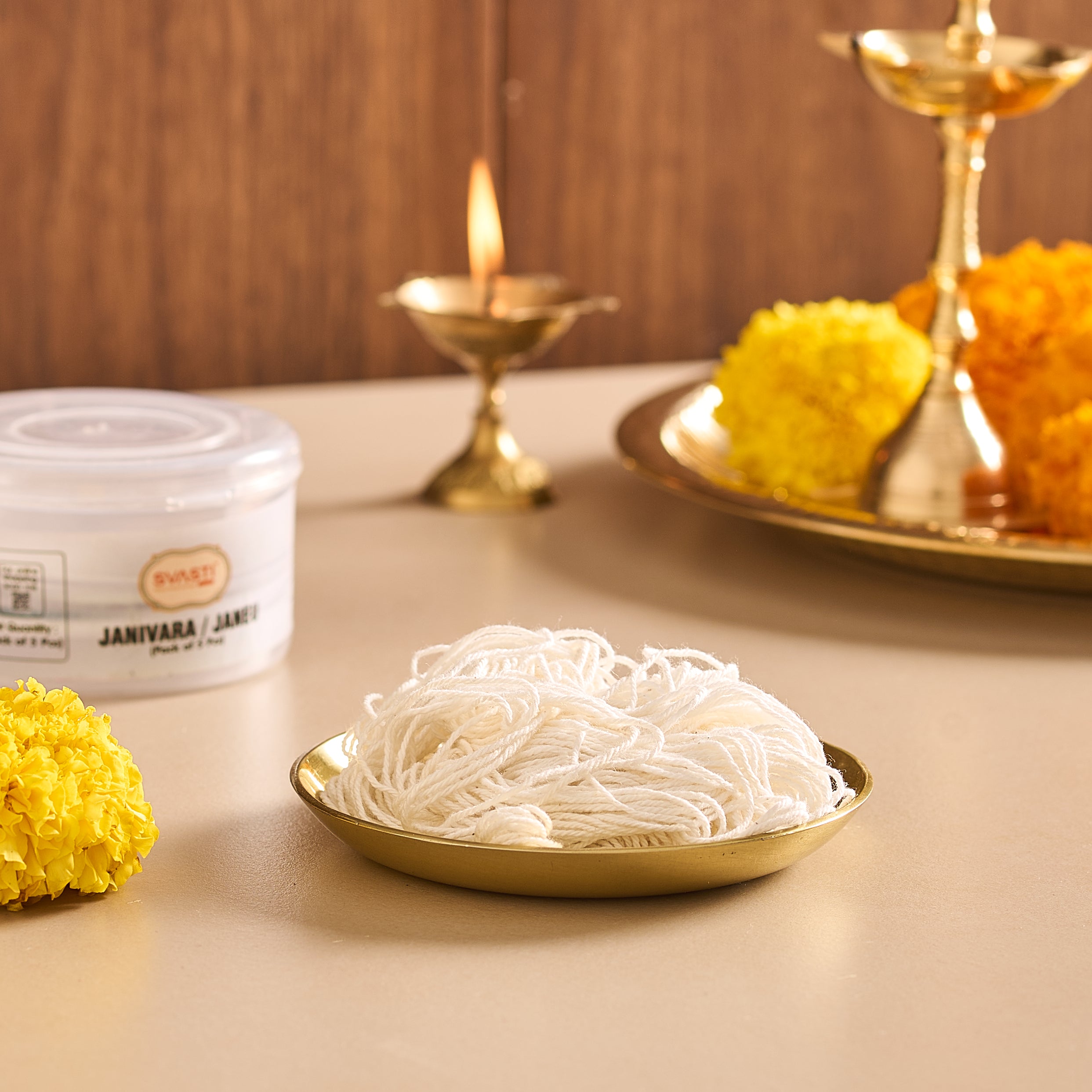 Noodles on a gold plate with decorative marigold flowers and a candle in the background