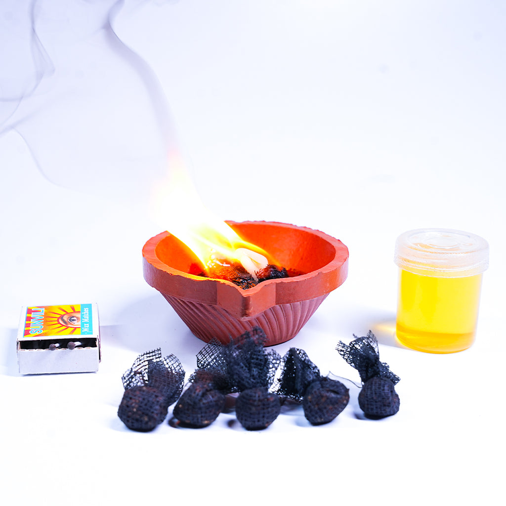 Heart-shaped fire pit with burning wood, matches, and a container of liquid on a white background