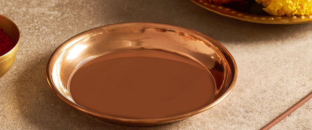 Bronze plate on a stone surface with marigold flowers and red powder