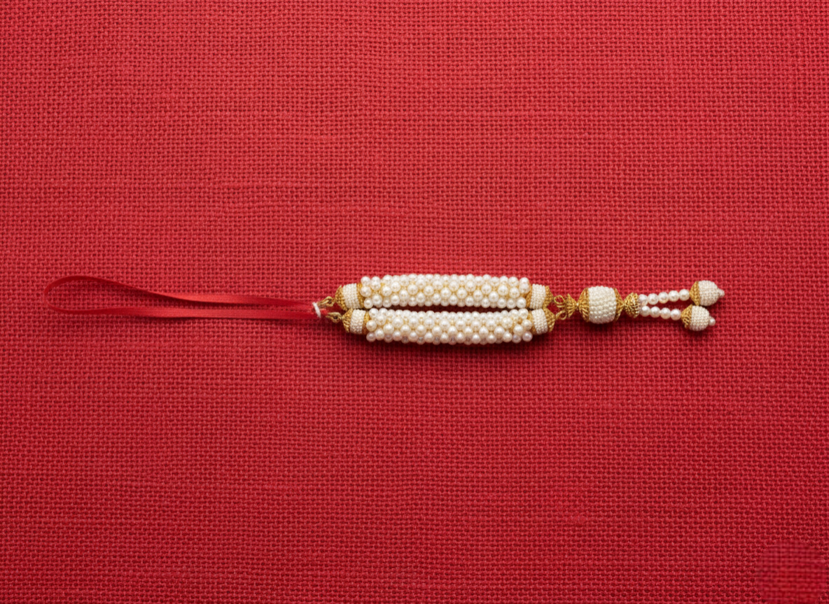 Decorative string with pearls and gold accents on a red background