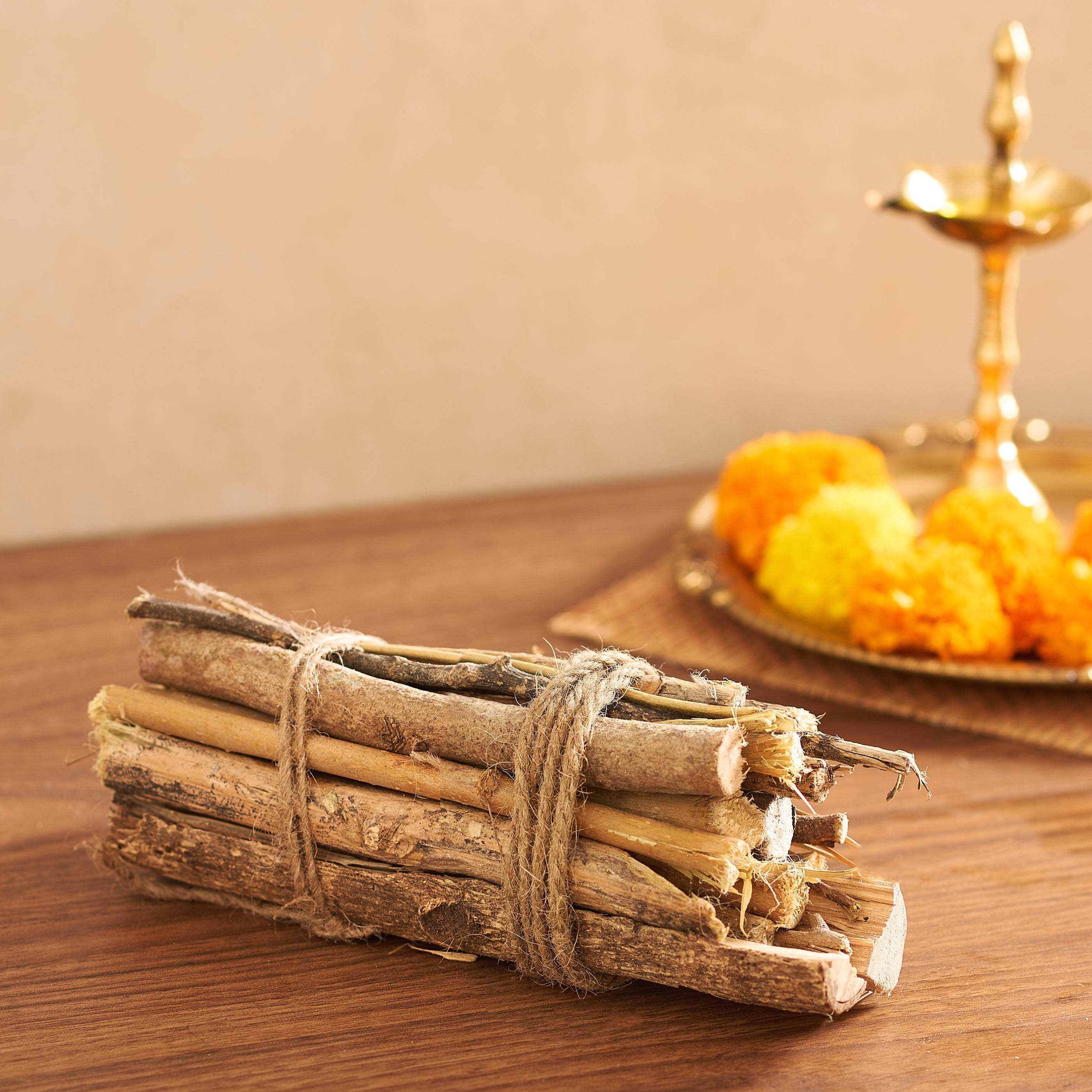 Bundled sticks tied with twine on a wooden surface with decorative items in the background.