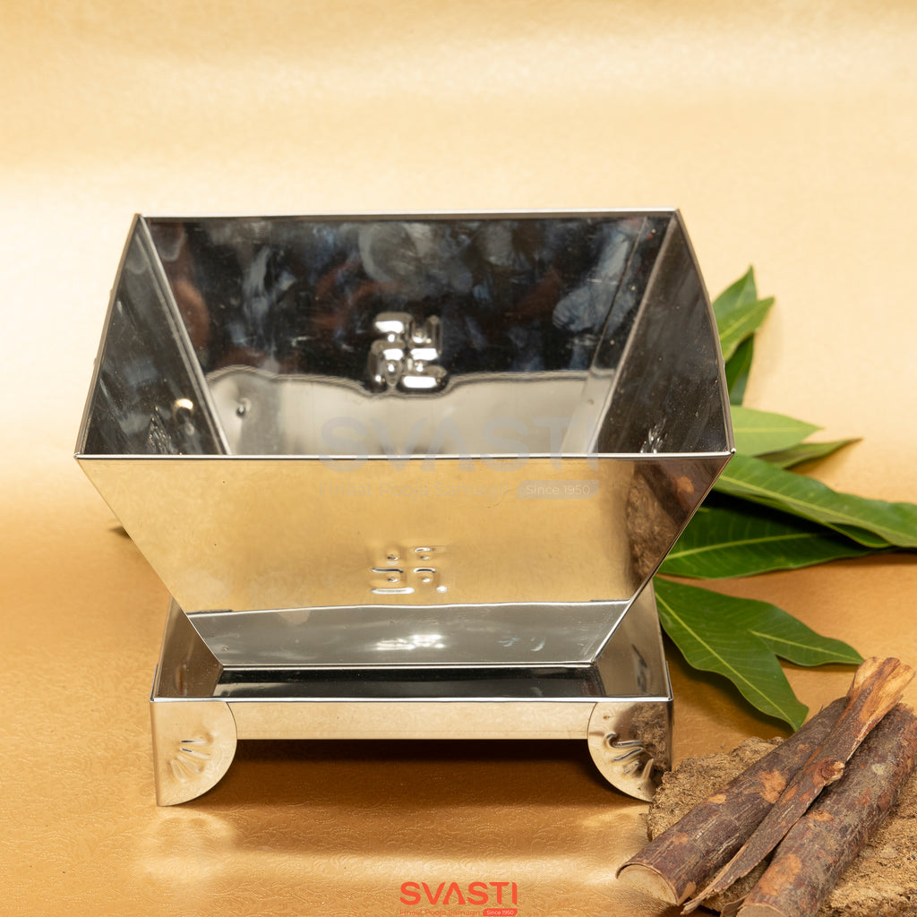 Metallic box with 'SVASTI' branding on a wooden surface with cinnamon sticks and leaves.