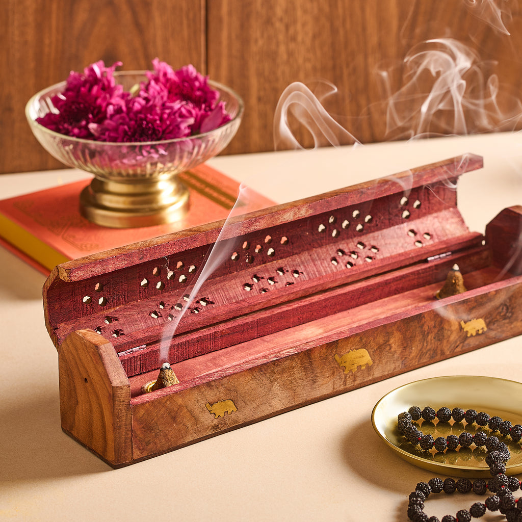 Incense burner with smoke, bowl of purple flowers, and rosary on a wooden surface