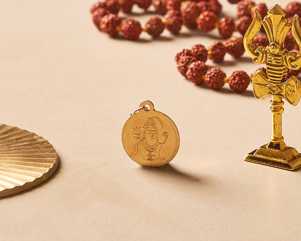 Gold pendant, rosary beads, and decorative item on a beige background