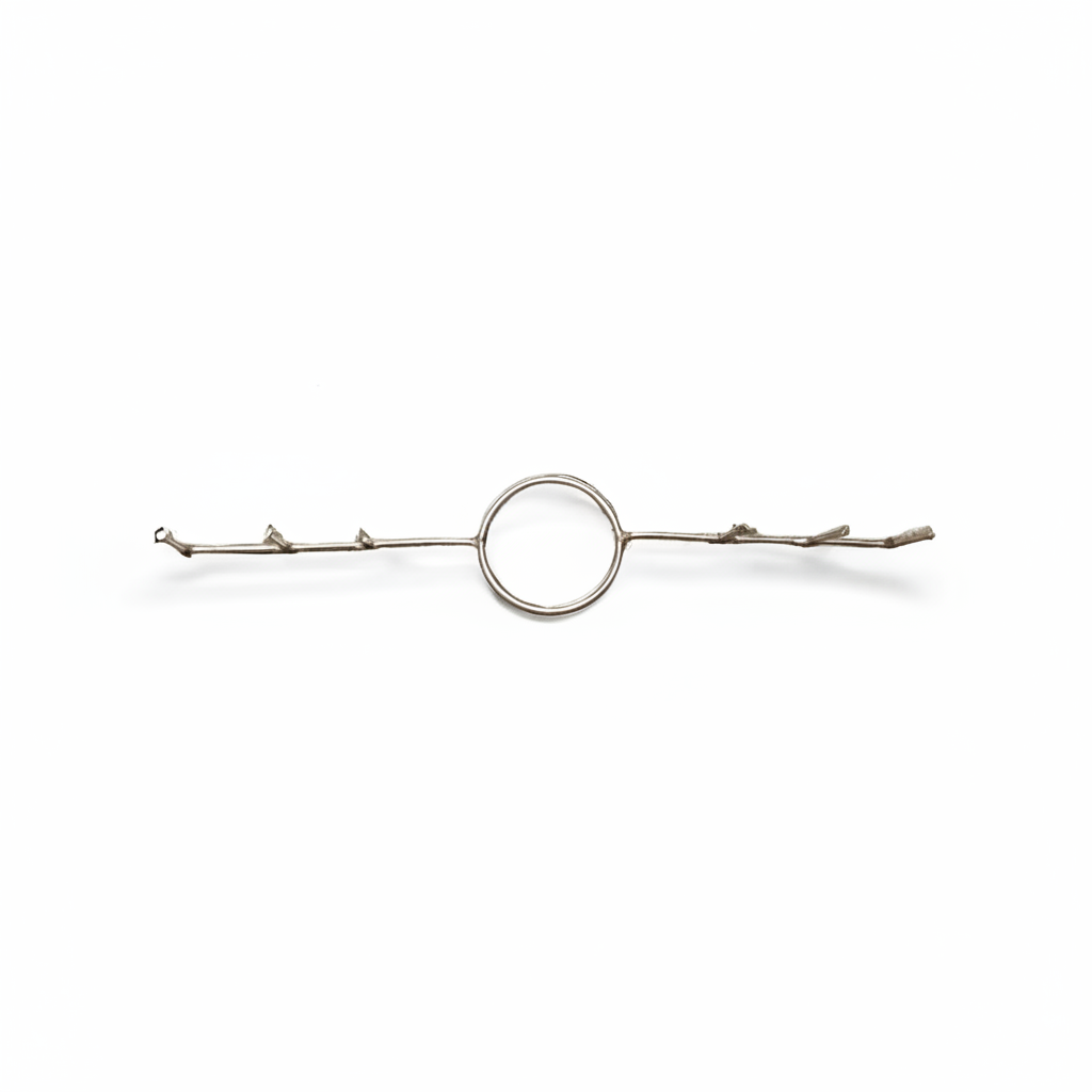 A silver-toned metal hair accessory featuring a central circular loop connected to two thin, twig-like side bars with small branch details, shown on a plain white background.