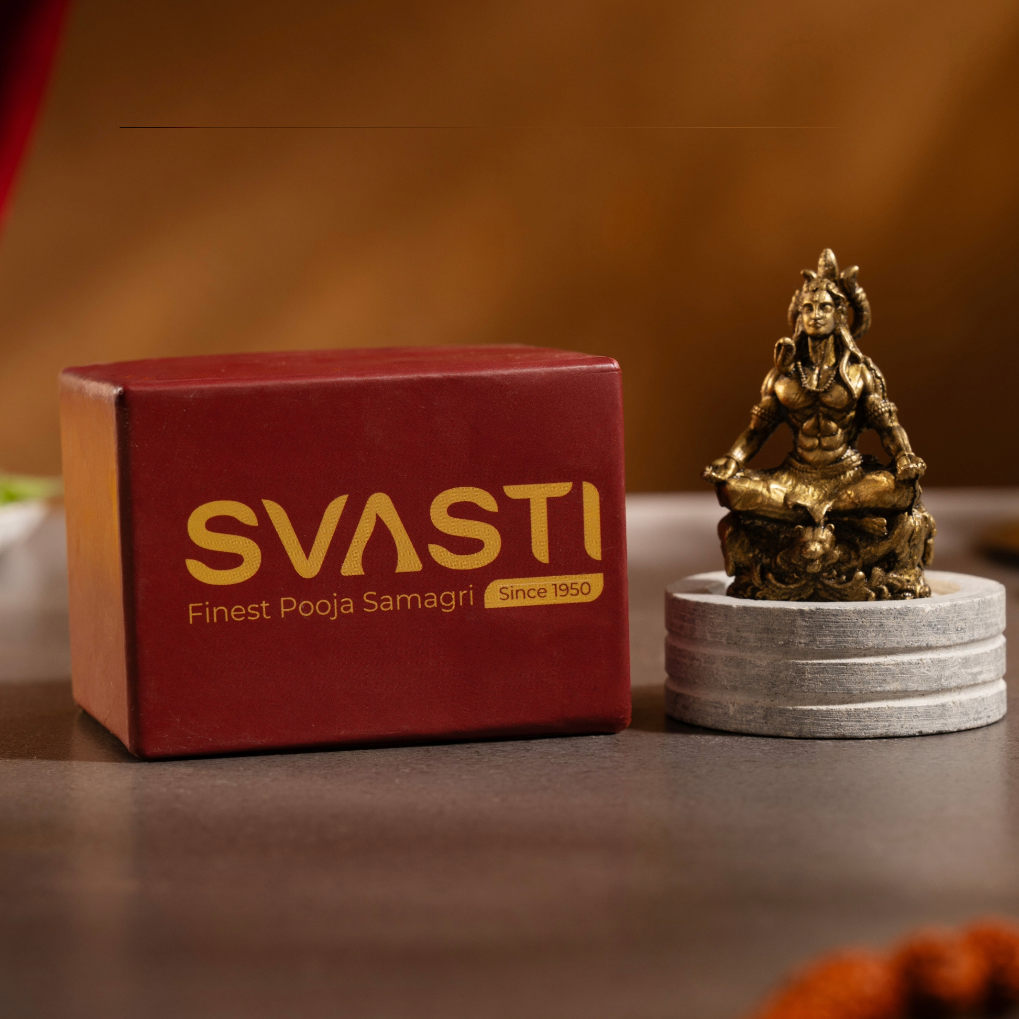 Small brass Shiva idol arranged inside a compact home temple shrine setup next to small ritual accessories to show scale.
