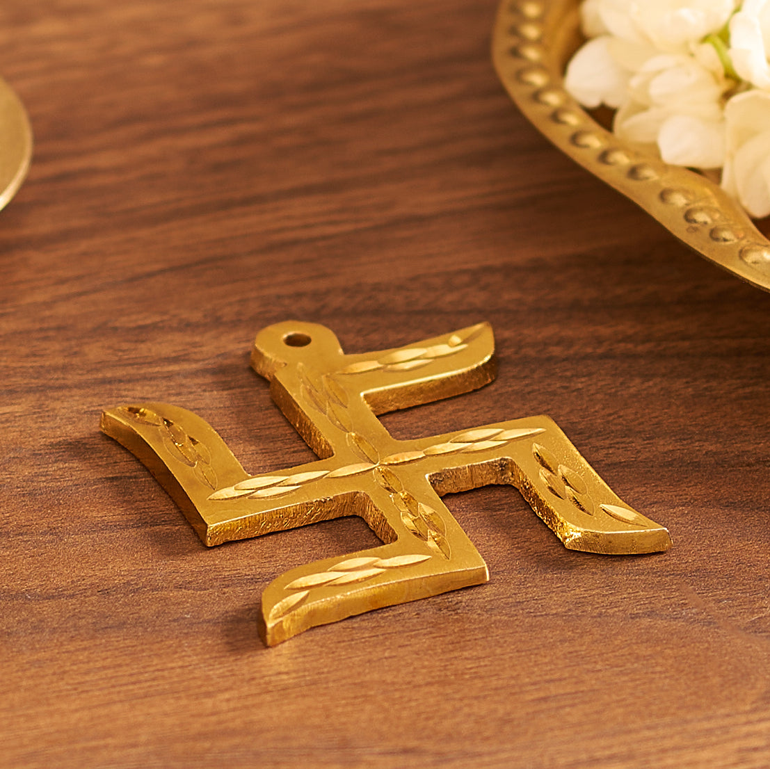 Gold swastika pendant on a wooden surface