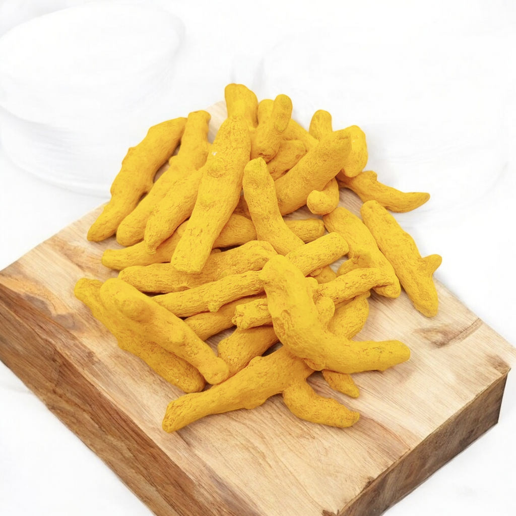Turmeric roots on a wooden cutting board with a white background