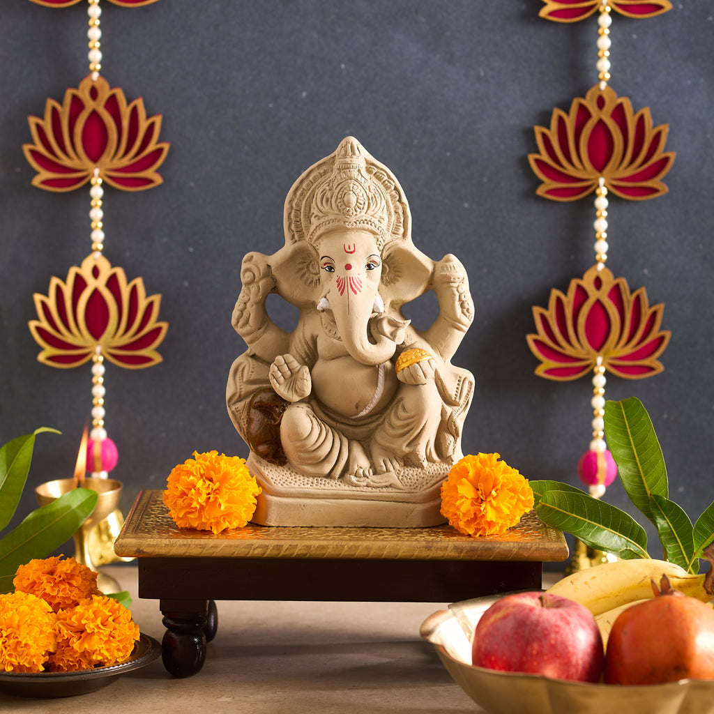 Statue of Ganesha with marigold flowers and fruits on a dark background