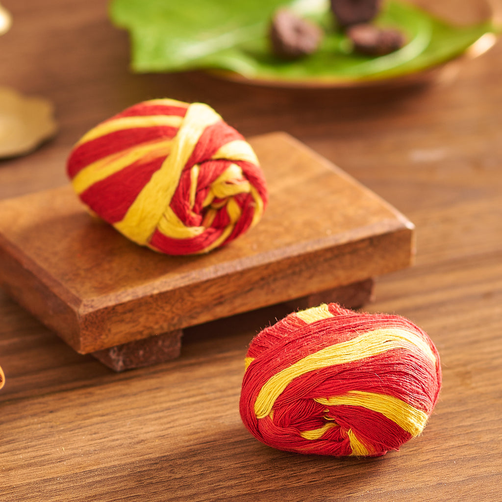 Red and yellow striped fabric rolls on a wooden surface with a blurred green plate in the background.