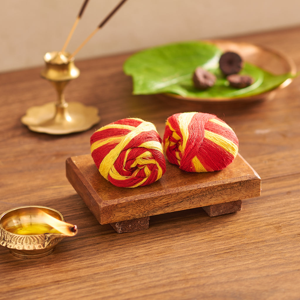 Two red and yellow striped items on a wooden platform with incense and leaves in the background.
