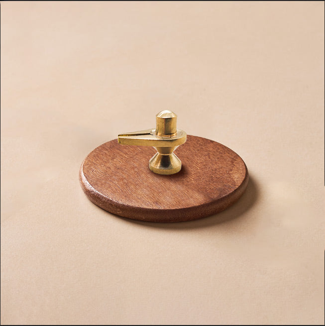 Round wooden coaster with a gold metal holder on a beige background