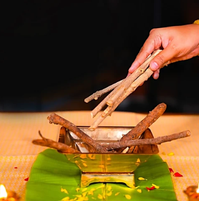 Hand placing sticks into a small stove on a leaf