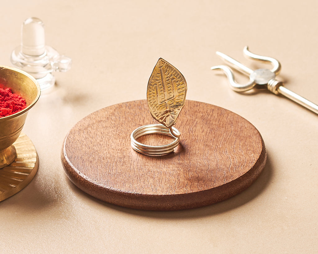 Wooden ring holder with a leaf design on a beige surface