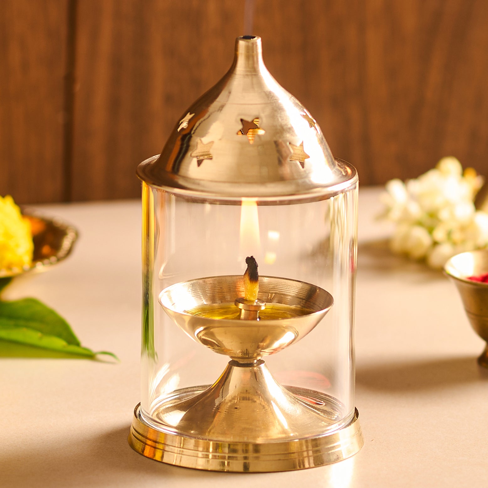 Brass oil lamp with a clear glass cover on a wooden surface.