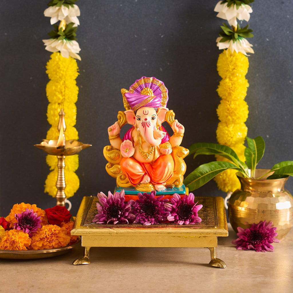 Decorative statue of a deity on a platform with flowers and lamps in the background