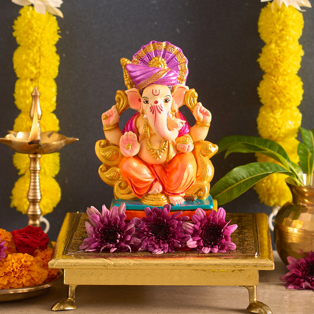 Colorful statue of a deity on a platform with flowers and yellow decorations in the background