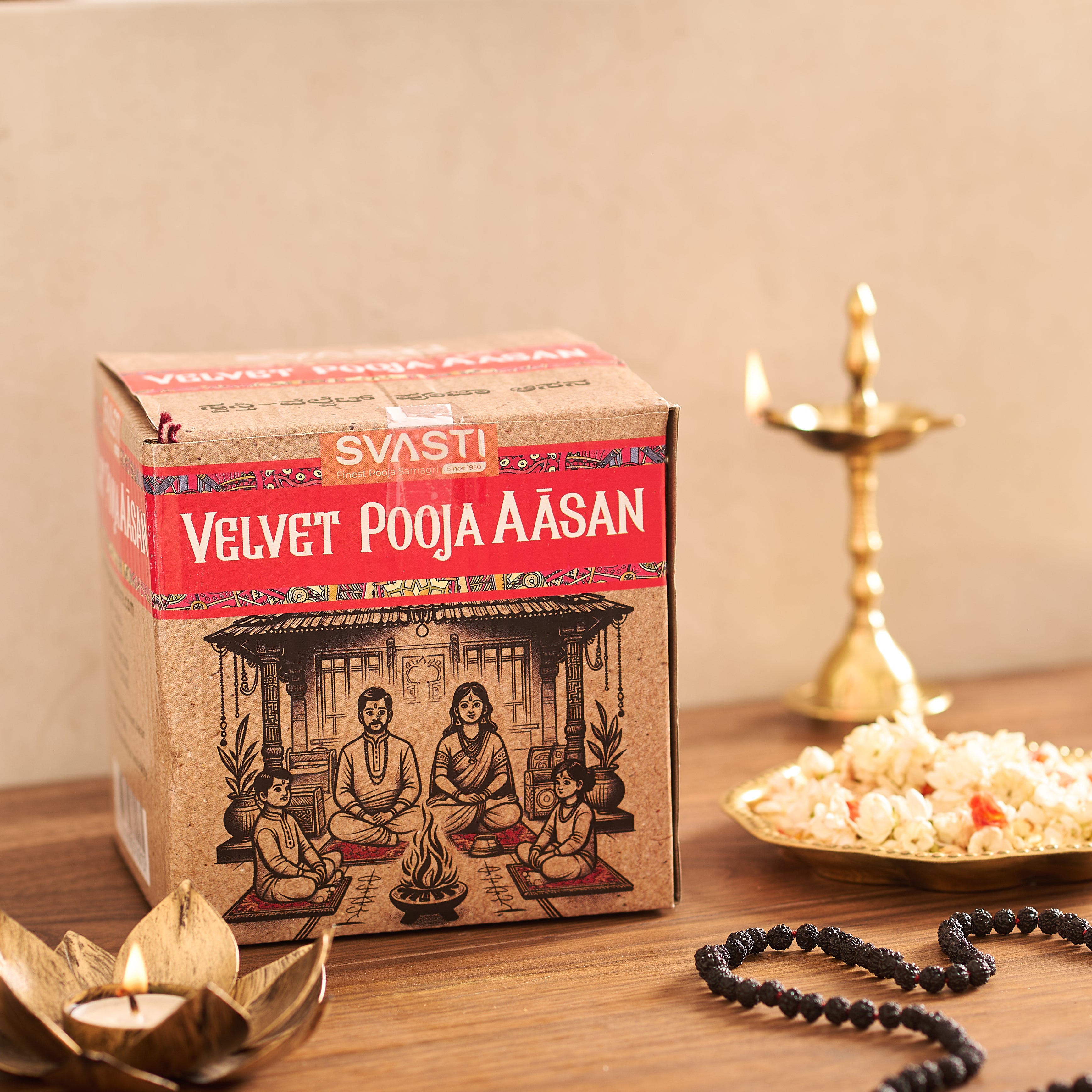 Box of 'Velvet Pooja Aasan' with candles and a plate of popcorn on a wooden surface.