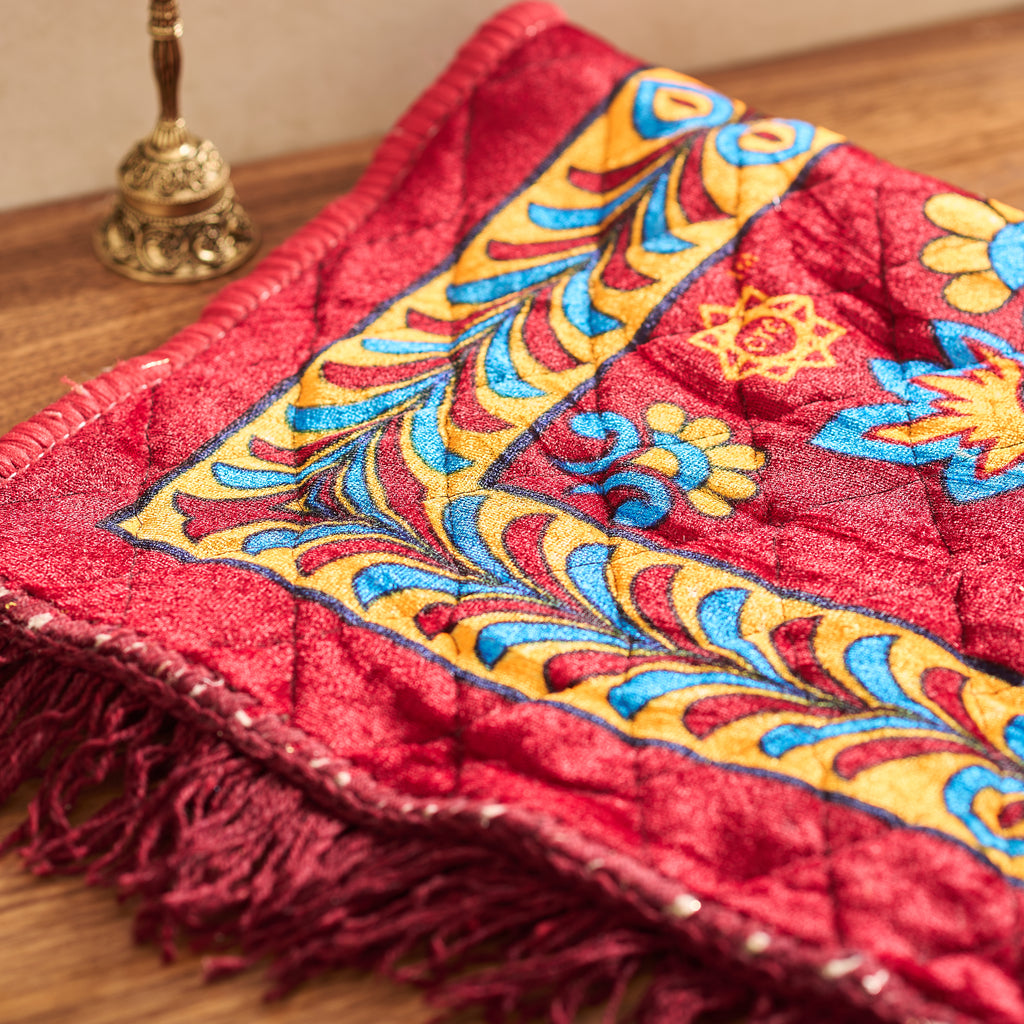 Red embroidered fabric with colorful patterns on a wooden surface