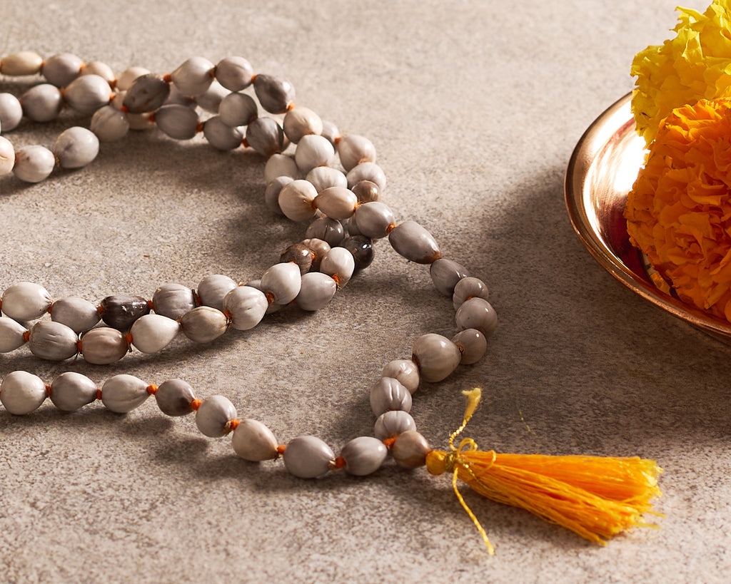 Meditation beads with a yellow tassel on a textured surface