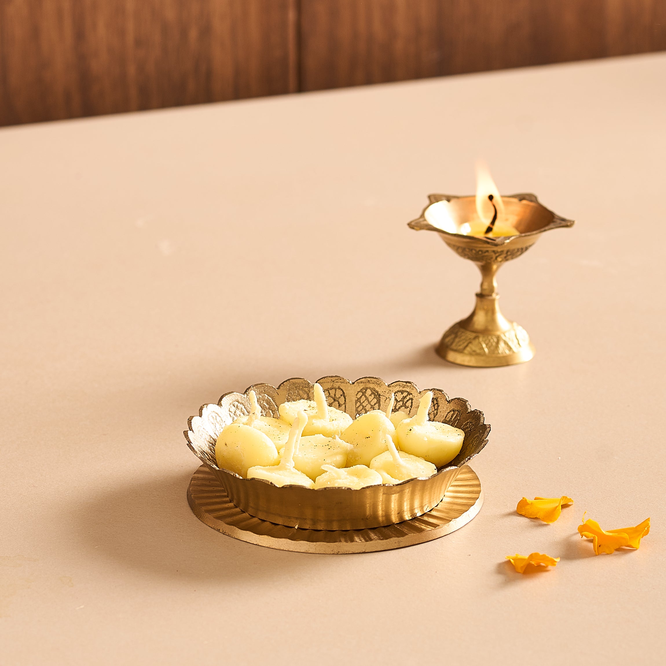 Decorative brass plate with lit candles on a beige surface